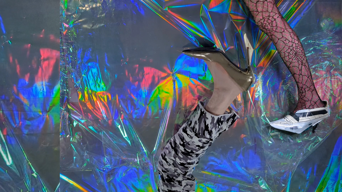 A leg dressed in camouflaged wearing a golden high heel is interacting with another leg wearing a high heel in the shape of a boat. Around them is iridescent foil.