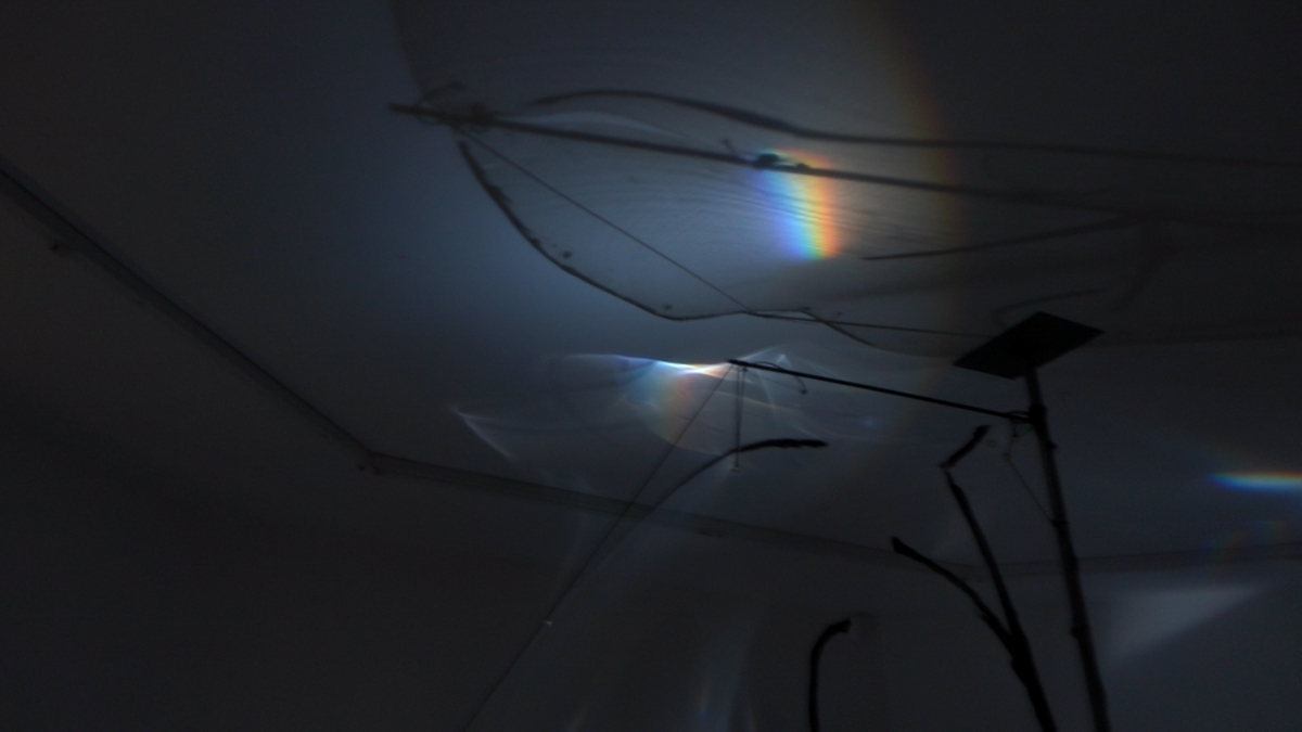 Detail view of refracted spectral light on ceiling and a translucent foil sail.