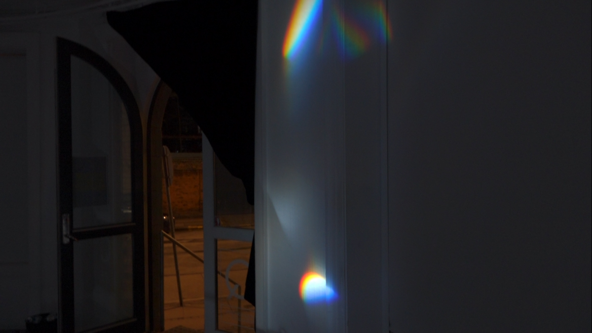 Detail view of refracted spectral light on a wall within the exhibition space.